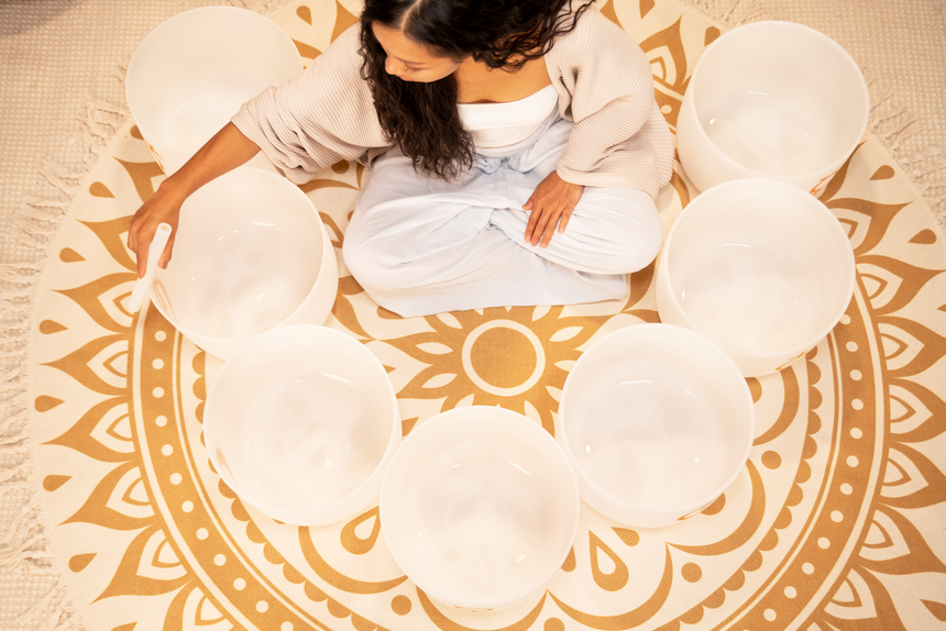 MEINL PCSBSETCHA set of seven white-frosted crystal singing bowls with gold planetary symbols – close overhead view of a singing bowl being played.