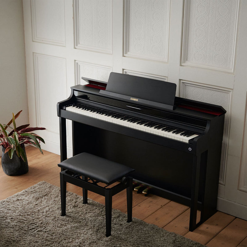 Casio AP-550BK digital piano in black – three-quarter view in a room with a black bench.