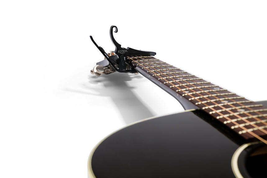 Kyser KG6LTA Low-Tension-Kapodaster für Stahlsaitengitarre, schwarz – am Akustikgitarrenhals angebracht.